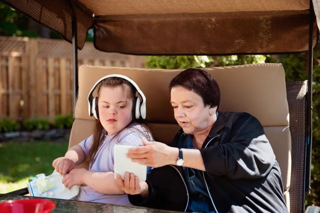 A support worker helping an NDIS participant use a tablet together outdoors